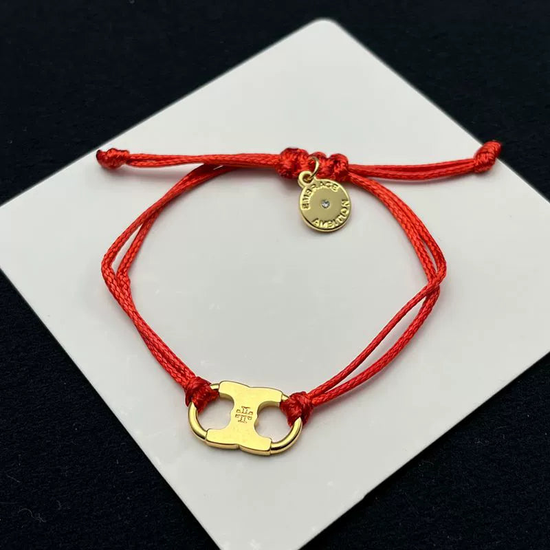 Red woven adjustable drawstring bracelet with gold clover charm and round coin tag
