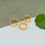 Gold-tone circular logo patchwork rings, three-piece set on display