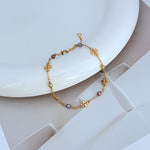 Perlen-Logo Armband mit goldfarbener Kette, weißen und farbigen Perlen