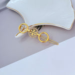 Round diamond-studded hair clip with patterned center disc in gold-tone metal