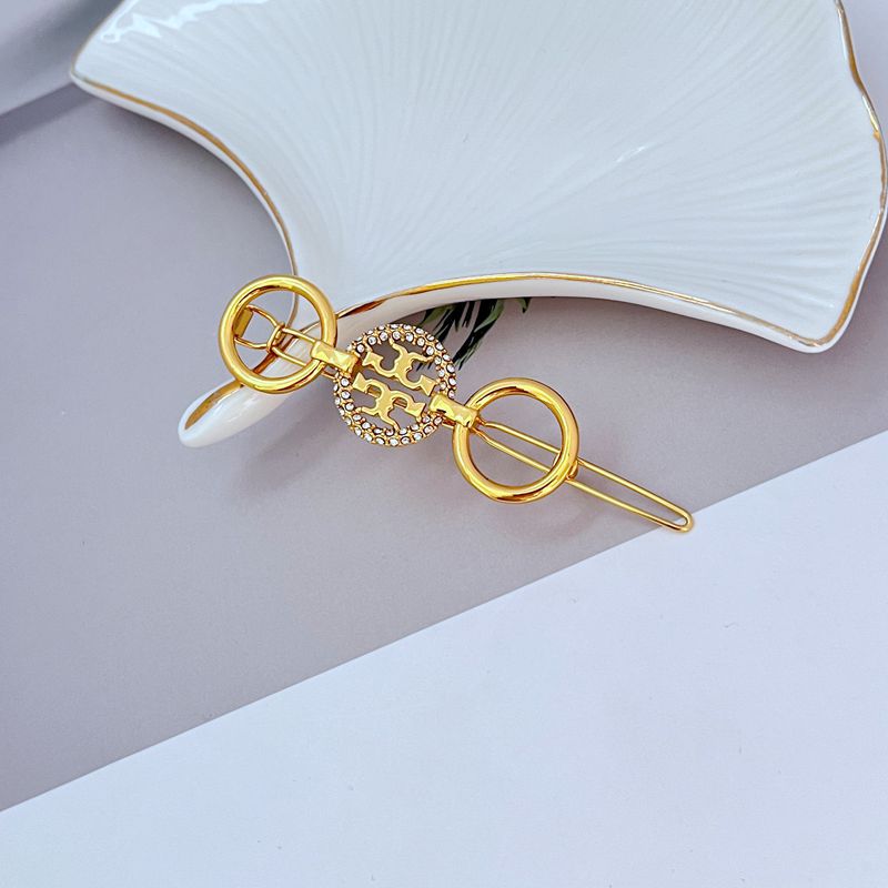 Round diamond-studded hair clip with patterned center disc in gold-tone metal