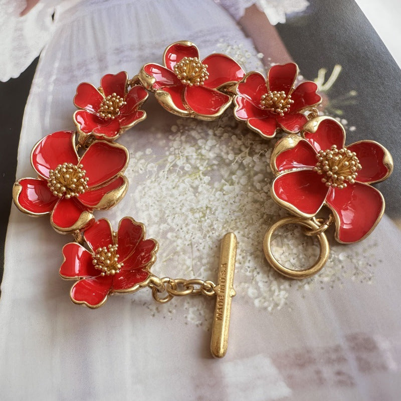 Enamel floral bracelet with gold-tone chain, red petals, and raised bead centers
