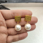 Gold square tag earrings with large white pearl drops