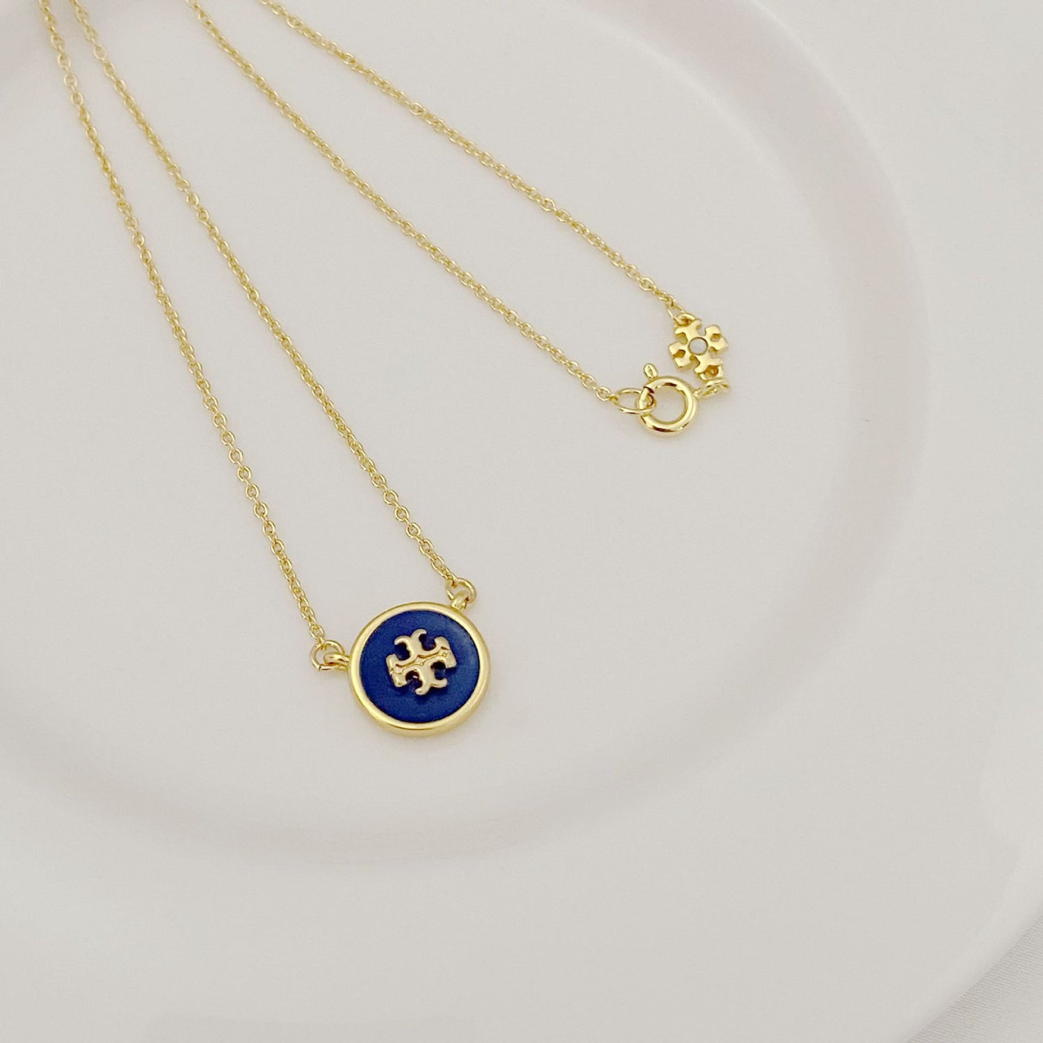 Gold-tone chain necklace with round blue enamel logo pendant