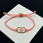 Pulsera con cordón rosa ajustable y dije esmaltado rosa con marco dorado