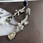 Clip-on earrings with silver-tone branch design, dark blue stones, crystal teardrops, dangling charms