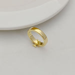 Gold-tone geometric letter-style ring, side view with raised emblem details
