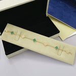 Goldfarbenes Kleeblatt-Armband mit grünen Motiven und funkelnden Zwischenstücken, mit Verschluss