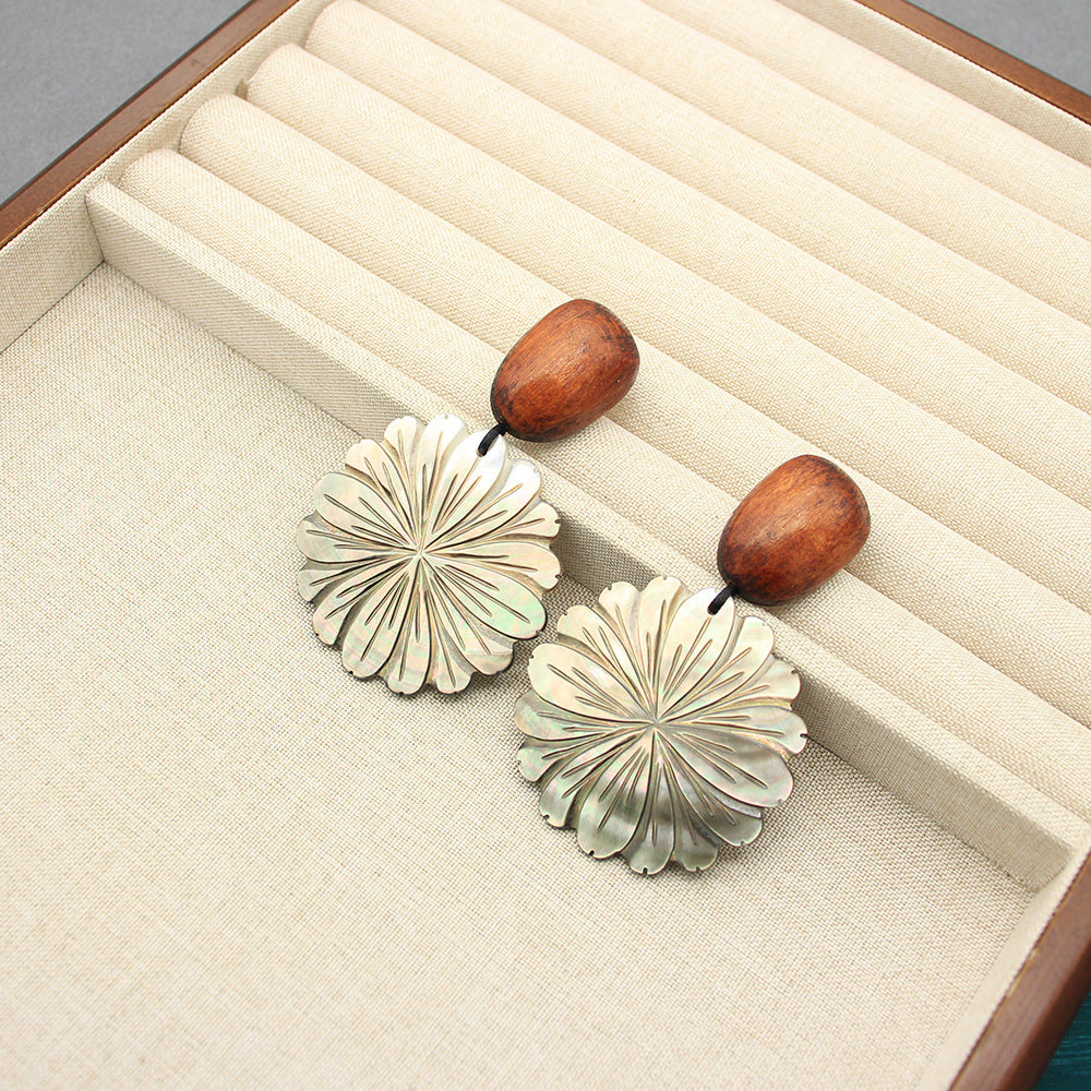 Flower-shaped mother-of-pearl earrings with rounded brown posts and detailed white petal petals