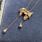 Gold-tone bow crystal tassel necklace close-up with three round crystal dangles