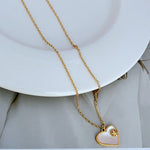 Heart-shaped shell pendant on gold chain with light enamel heart and gold inner detail