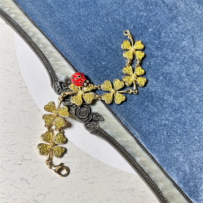 Gold-tone ladybug and four-leaf clover charm bracelet with clover and rose accents
