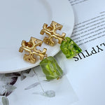 Green irregular acrylic logo pendant earrings with gold-tone geometric cross and drop charm