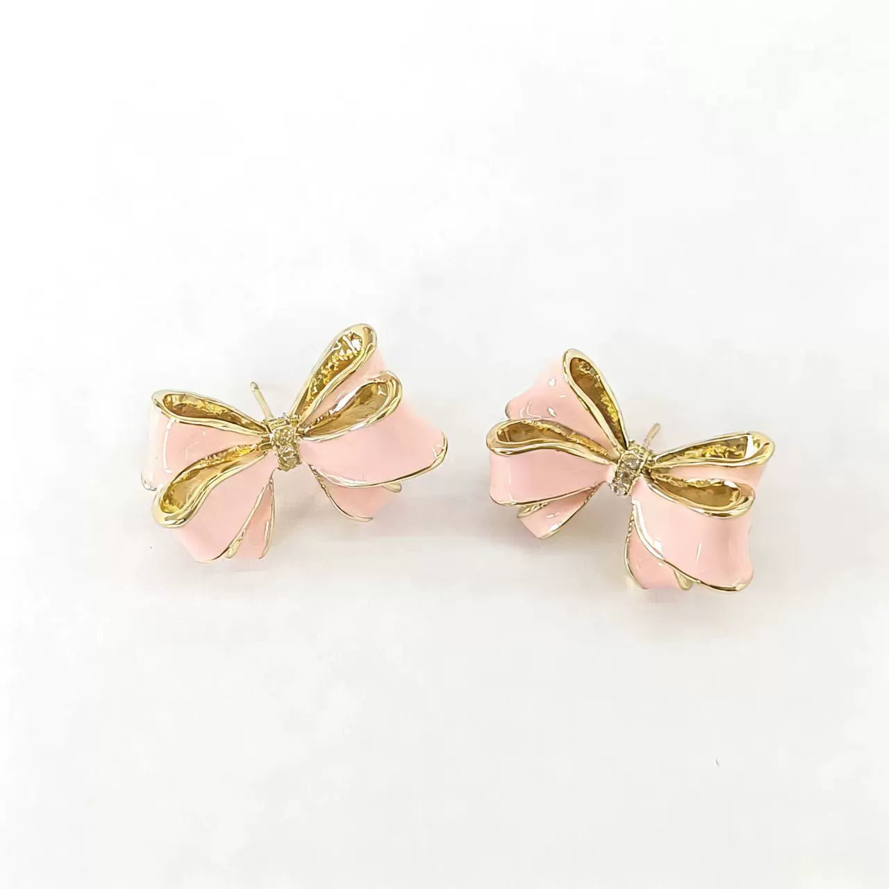 Gold-tone bow pearl drop stud earrings with pink enamel, shown separately