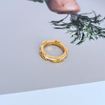 Gold-tone geometric circle ring with white enamel-like sections on the band