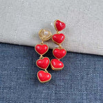 Red heart long drop earrings with gold-tone frames and a pearl-like top accent