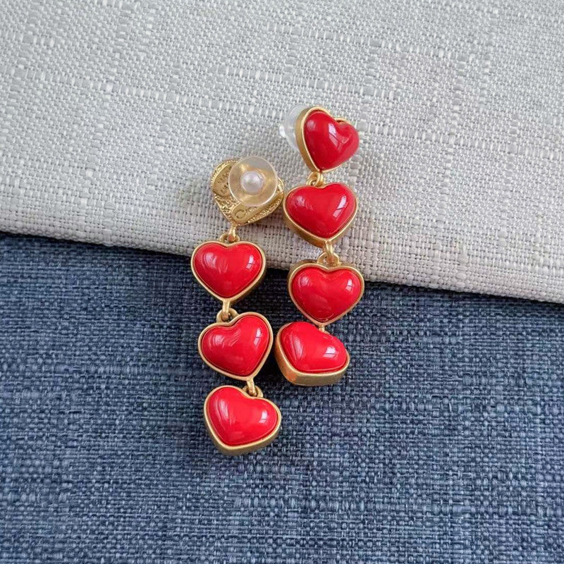 Red heart long drop earrings with gold-tone frames and a pearl-like top accent