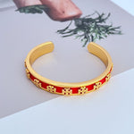 Offener Armreif mit rotem Emailband und goldfarbenem Logo-Muster