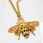 Gold bee pendant necklace with diamond-like pavé wings and black enamel dot detail