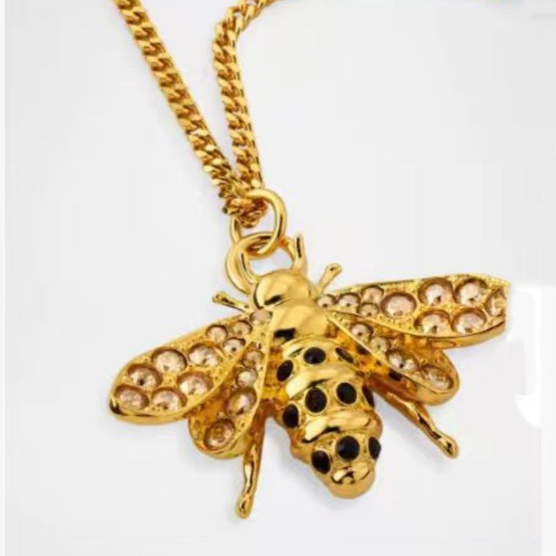 Gold bee pendant necklace with diamond-like pavé wings and black enamel dot detail