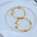 Gold-tone high-shine 3D logo round hoop earrings, hinged clasp, metal
