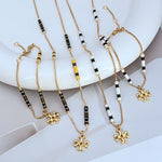 Gold-tone beaded charm bracelet with white and black enamel stations