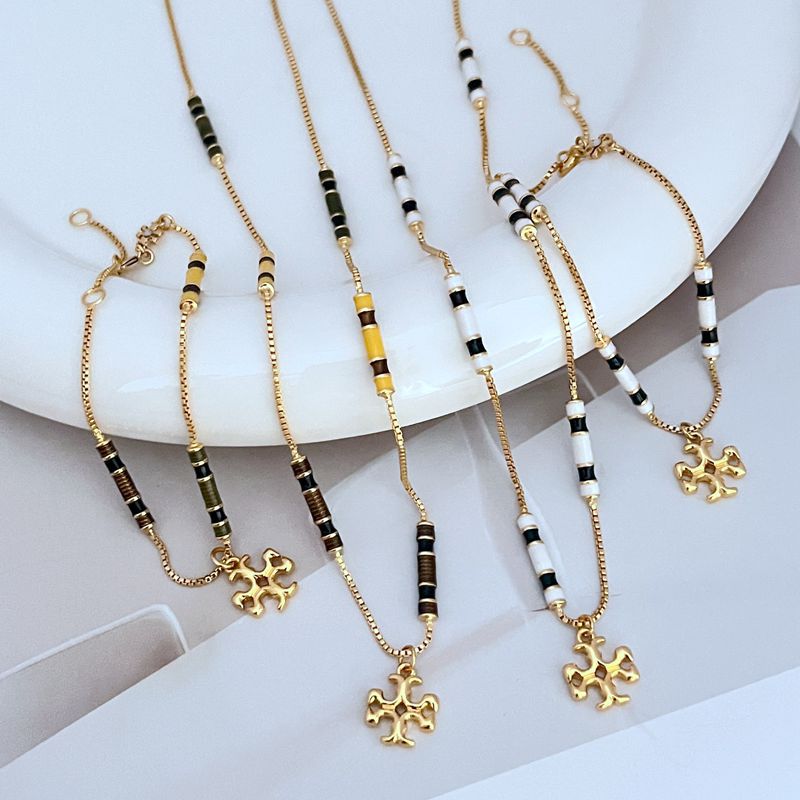 Gold tone beaded pendant bracelet with black and white beads and clover charm