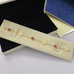 Goldfarbenes Armband mit dunkelroten Vierblatt-Anhängern und Glitzer-Steinen