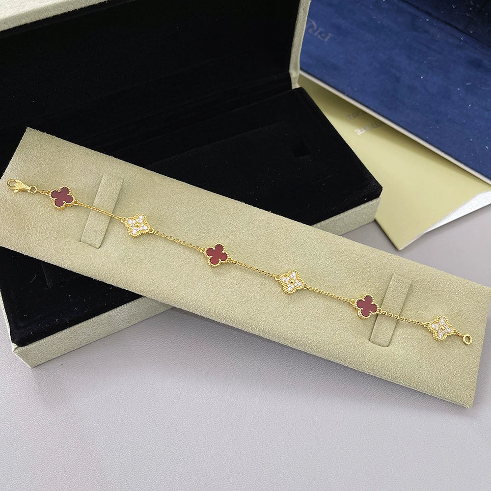 Goldfarbenes Armband mit dunkelroten Vierblatt-Anhängern und Glitzer-Steinen