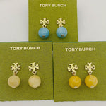 Blue agate pendant earrings with gold logo stud, shown on jewelry cards