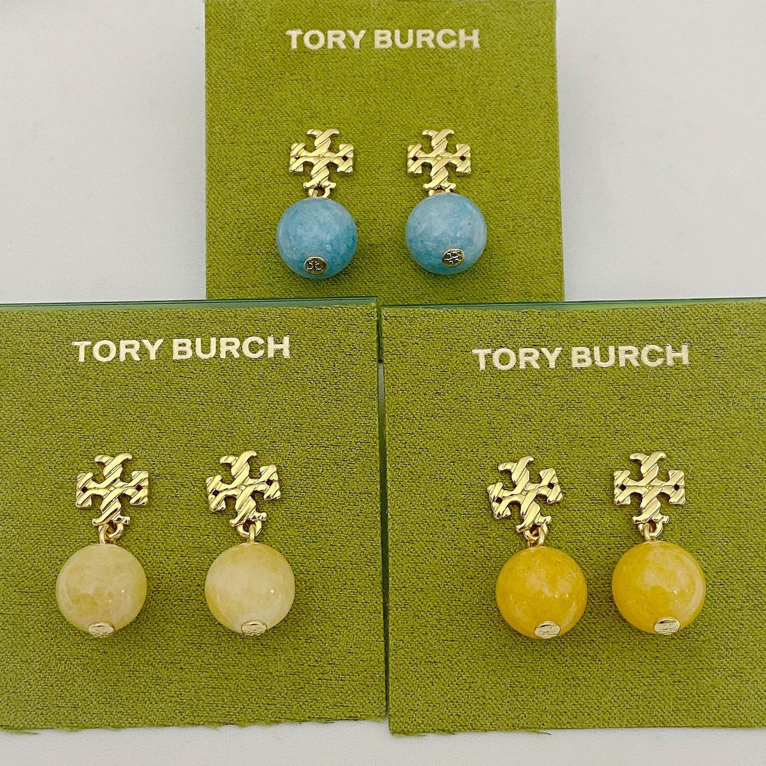 Blue agate pendant earrings with gold logo stud, shown on jewelry cards