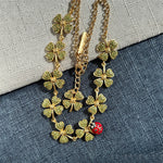 Green four-leaf clover necklace with red ladybug charm and layered gold chain