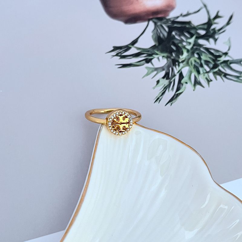 Top view of gold-tone openwork logo ring with small clear stone halo