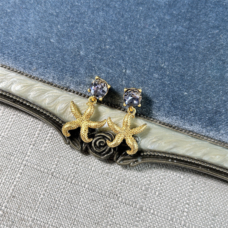 Gold starfish stud earrings with light-colored crystals