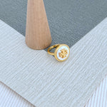 Round enamel metal ring with white shell center and gold-tone bezel
