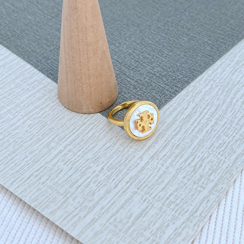 Round enamel metal ring with white shell center and gold-tone bezel