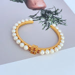 Pearl Logo open bangle with white pearls and gold-tone center motif