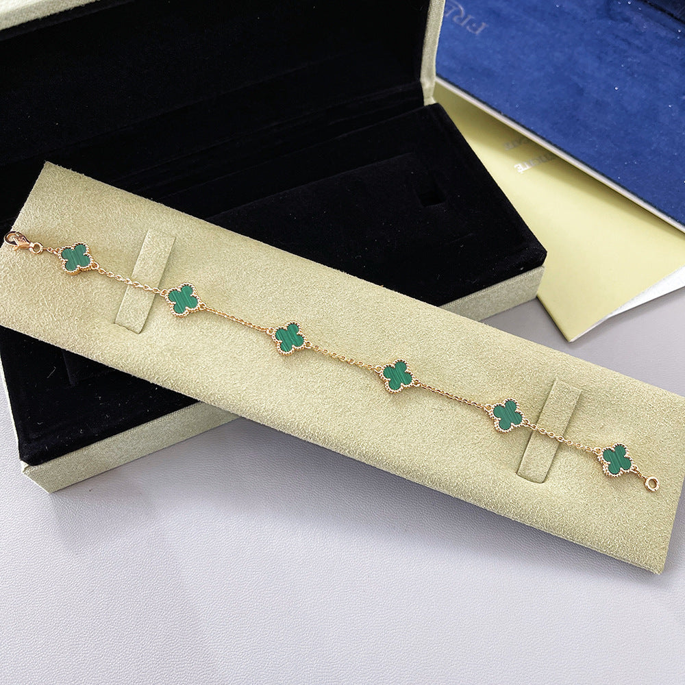 Gold tone bracelet with green clover charms spaced along a delicate chain