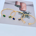 Gold-tone open bangle with round enamel discs in green, blue, and white.