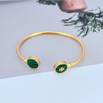 Round enamel shell open metal bangle with green round discs and gold-tone clasp.