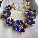 Enamel floral bracelet with gold-tone chain, dark blue petals, and bead-centered blossoms