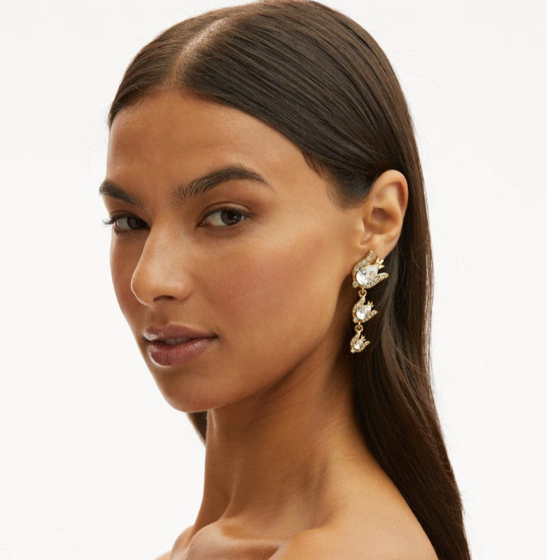 Gold-tone floral zircon drop earrings with clear stones worn on model