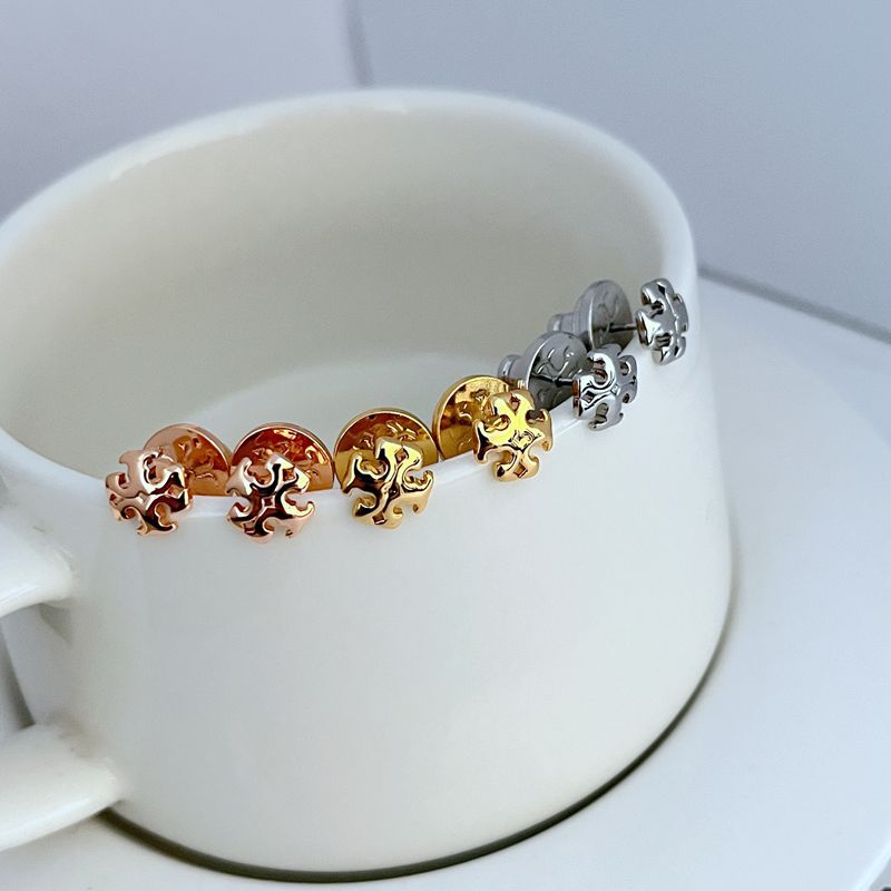 Logo stud earrings in rose, gold, and silver tones on display stand