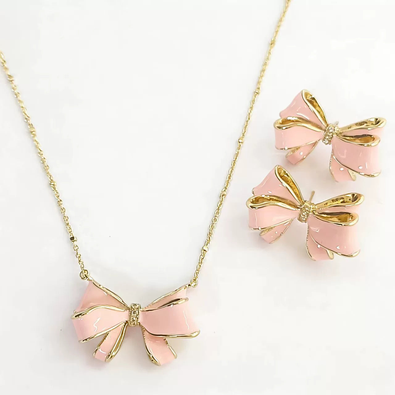 Bow pendant necklace with pink enamel and white pearl drop, with stud earrings
