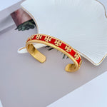 Offener Armreif mit rotem Emailband, goldfarbenem Logo und C-Form-Öffnung