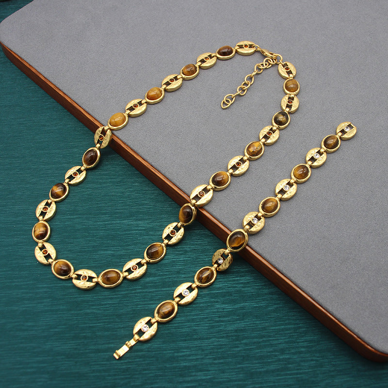 Gold-tone chain necklace with oval blue beads and decorative side clasp details