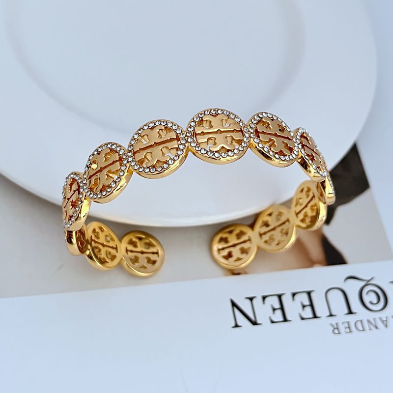 Gold-tone circular openwork logo bangle with diamond-studded bezel links