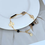 Tory Burch enamel agate logo bracelet with black beads, gold bar charm, and puzzle charm