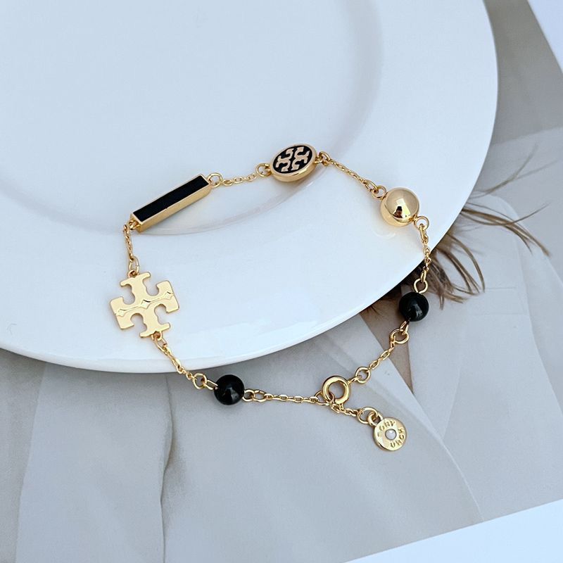 Tory Burch enamel agate logo bracelet with black beads, gold bar charm, and puzzle charm