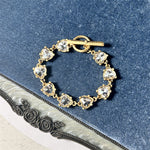 White crystal heart link bracelet with gold-tone chain and round clasp bar